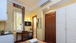 Een hotelkamer met een bed, een bureau, een stoel, een televisie, een kledingkast en een airconditioning.