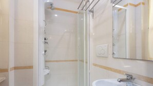Een badkamer met een glazen douchecabine, een wit wastafelmeubel en een spiegel.
