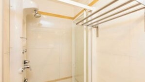 Een badkamer met een douchecabine van glas, een handdoekhouder en een toilet.