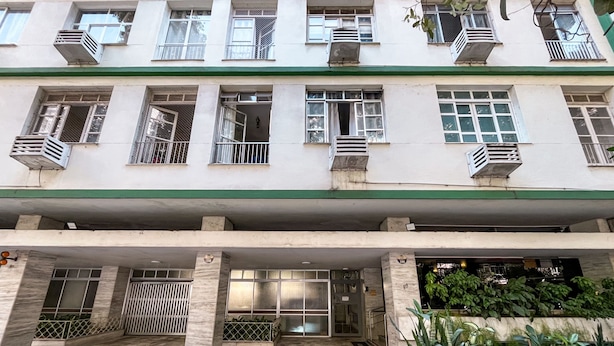 A multi-story building with a green and white facade, multiple balconies, and a tiled entrance area with potted plants. - 15min From Flamengo Beach Oc107b (Rio de Janeiro)