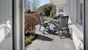 Un patio exterior con una mesa y sillas, una planta en maceta y vistas a una colina.