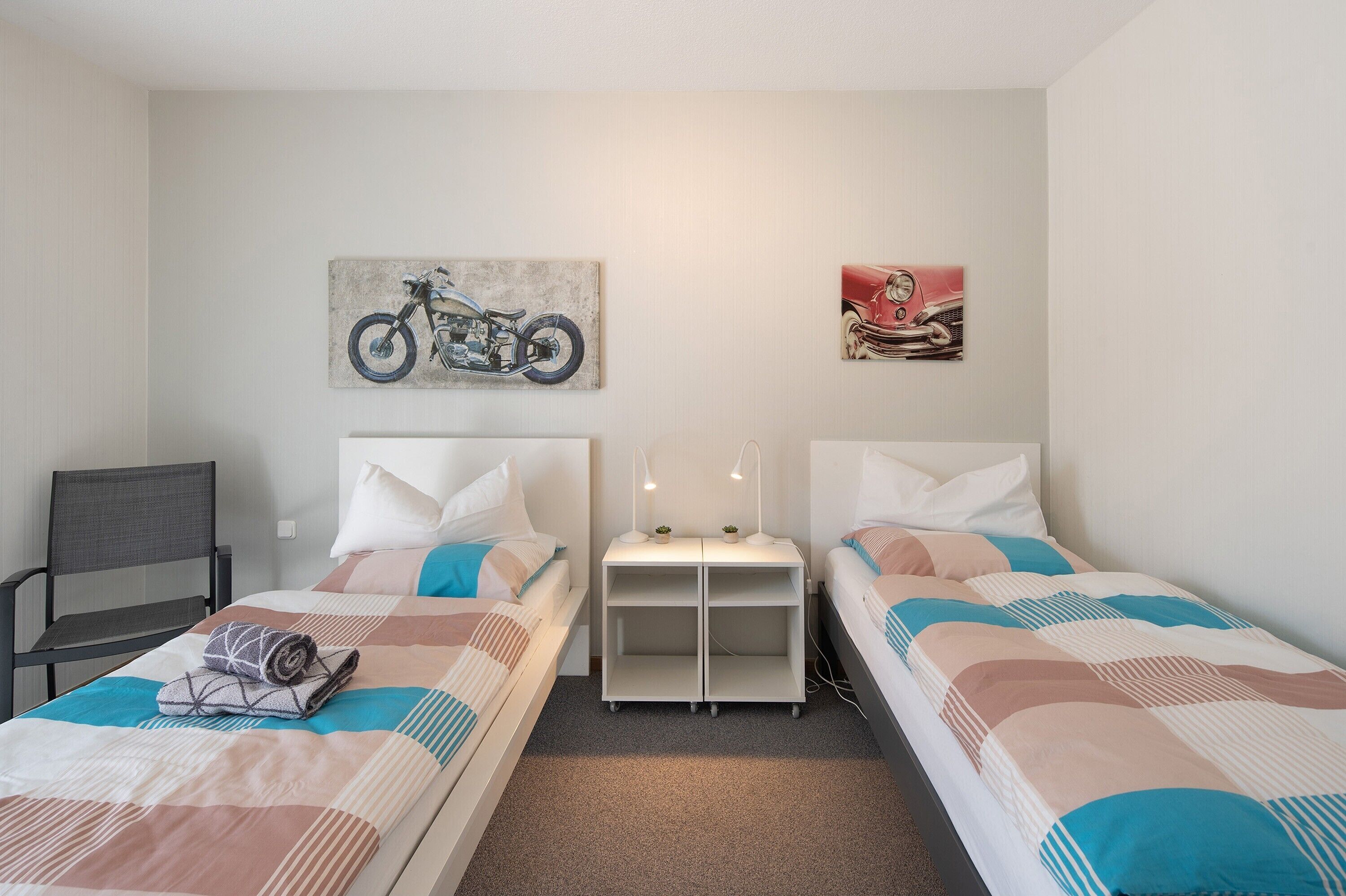 Une chambre double avec deux lits, un petit bureau, une chaise et des œuvres d’art murales.