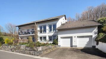 Ein zweigeschossiges Haus mit Garage, einer Steinmauer und blauem Himmel.