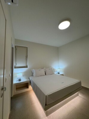 Ein Schlafzimmer mit Bett, Nachttischen, einem Spiegel und einer Deckenleuchte.