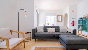 Ett modernt vardagsrum med en grå soffa, en trästol, ett litet sidobord och ett grönt skåp.
