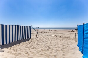 A sandy beach with a striped barrier and a blue tarp. - Cozy Beachfront Retreat With Scenic Terrace (Koudekerke)