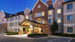 A multi-story hotel with a central entrance, large windows, and a brick facade. - Accessible Suite in Ballantyne w/ Free Breakfast (Charlotte)
