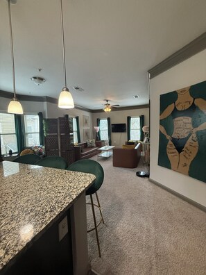 A modern kitchen with granite countertops, bar stools, and pendant lighting. - Velvet Vibes Retreat - A Corporate Work, Play, Stay Getaway (Pooler)