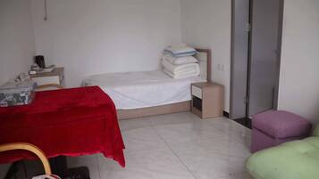 Una habitación pequeña y limpia con cama, escritorio, silla y una mesita.