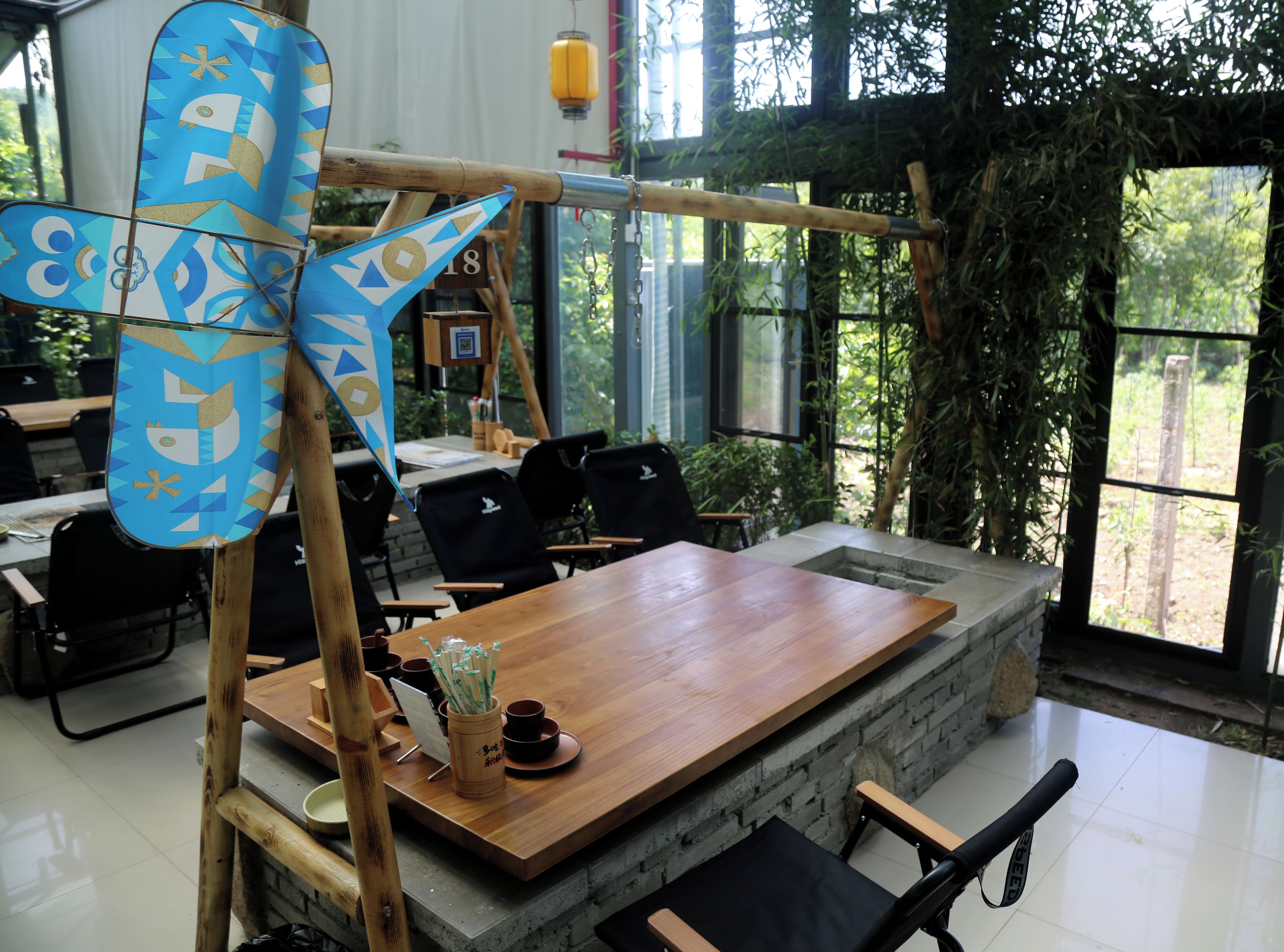 Un espace repas comprenant une table en bois, des chaises et une structure décorative en bambou.