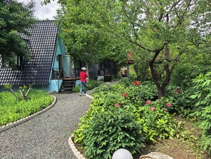 A pathway leading to a building with a tiled roof, surrounded by lush greenery and flowering plants. - Near Mutianyu Country Villa (Huairou)