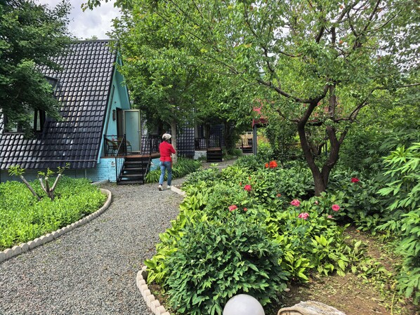 A pathway leading to a building with a tiled roof, surrounded by lush greenery and flowering plants. - Near Mutianyu Country Villa (Huairou)