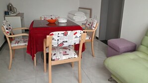 A dining area with a red table, four chairs with patterned cushions, a bowl, and a white cabinet with towels. - Near Mutianyu Country Villa (Huairou)