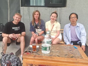 Quatre personnes sont assises à une table, devant une bouteille d’eau, un plateau et une paire de lunettes de soleil.