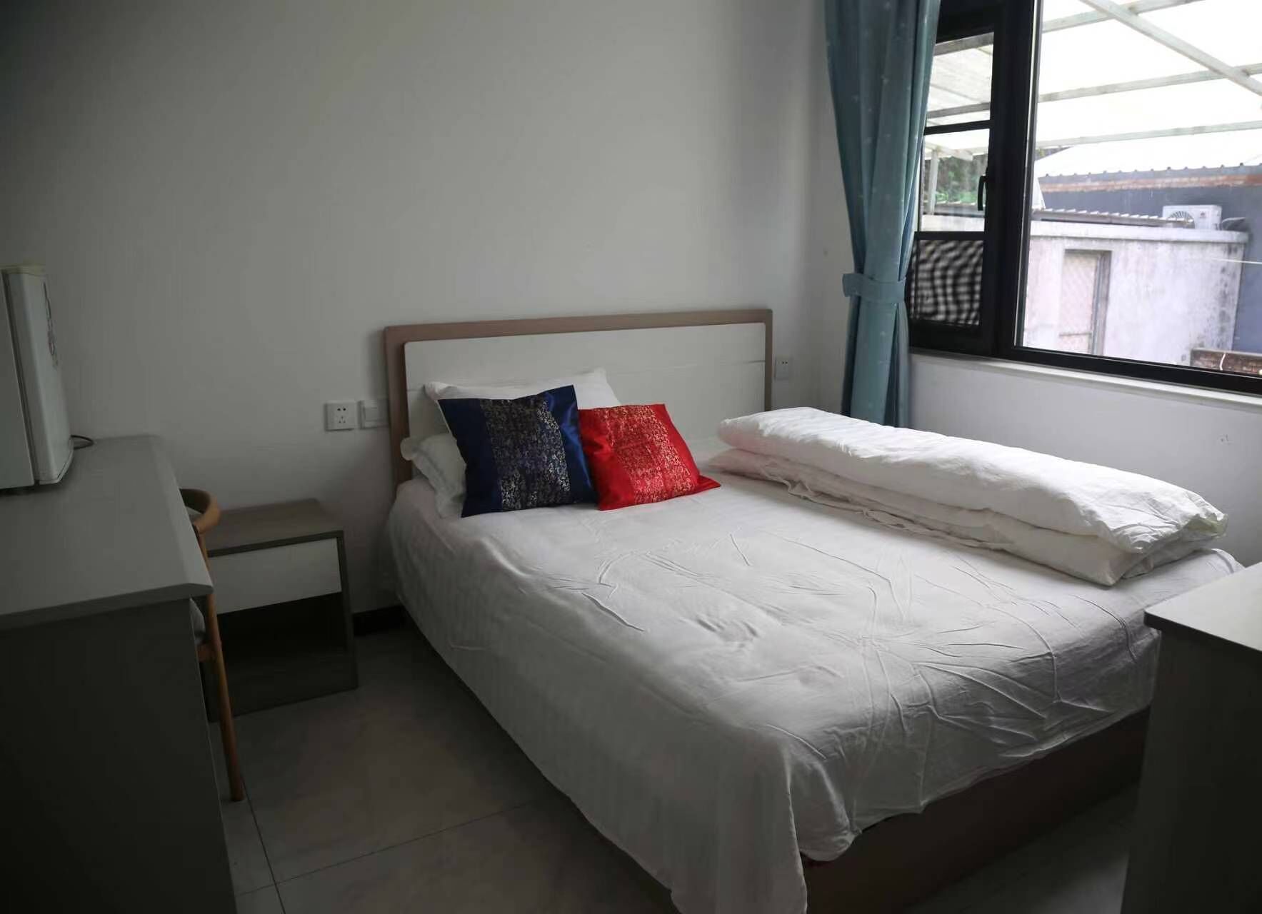 Una cama individual con ropa blanca, un cabecero de madera y dos almohadas.