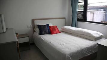 Una cama individual con ropa blanca, un cabecero de madera y dos almohadas.