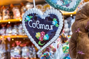 Eine herzförmige Dekoration mit dem Schriftzug 'Colmar' und farbenfrohen floralen Mustern.