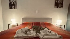 Hotelkamer met een bed, twee nachtkastjes, een hoofdeinde en twee aan de muur hangende foto's.