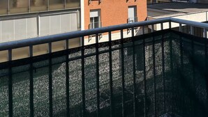 Een meerlaags woongebouw met balkons, een hekpoort en een heldere lucht.