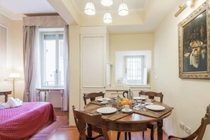 A hotel room with a dining area, a bed, and a painting on the wall. - Renaissance Elegance in the Heart of Florence (Firenze)