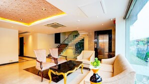 A hotel lobby with a staircase, seating area, and a large window. - Deluxeimperial Villa Delhi (New Delhi)