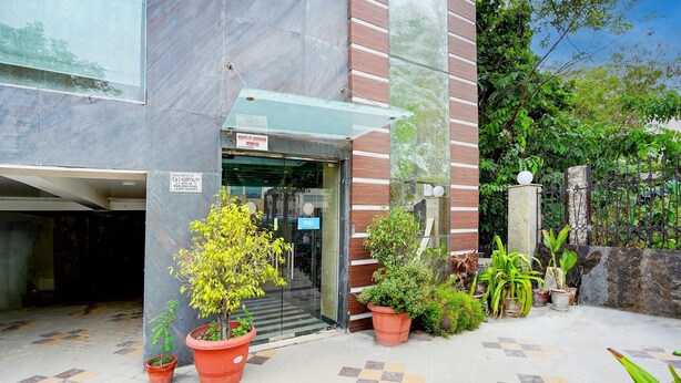 A hotel entrance with a glass door, potted plants, and a tiled floor. - Deluxeimperial Villa Delhi (New Delhi)