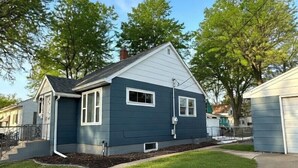 Une maison de plain-pied avec un jardin devant, un garage et un petit porche.