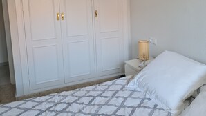 A bedroom with a bed, white curtains, a nightstand, and a wall-mounted lamp. - Apartment 5 minutes walk from the Fair. Ideal for couples. (Jerez de la Frontera)