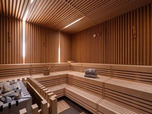 A sauna with wooden slats, benches, and a stone bench area. - 4 Star Holiday Home in Travemunde (Lübeck)