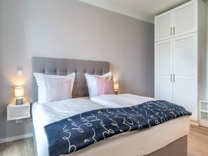 A bedroom with a bed, bedside lamps, a wardrobe, and a bedside table. - 4 Star Holiday Home in Travemunde (Lübeck)