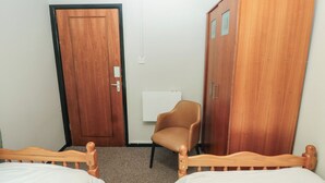 A room with two wooden beds, a brown chair, and two wooden wardrobes. - Cabin No. 15 - Salt and Fern Cabins (Port Talbot)