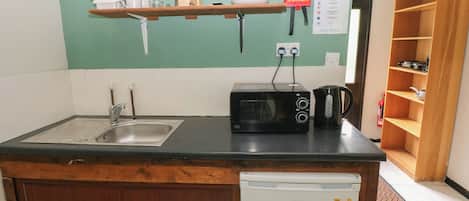 A compact kitchen with a sink, a microwave, a toaster, and a small refrigerator.