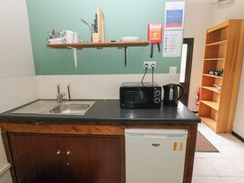 Cocina compacta con lavamanos, microondas, tostadora y refrigerador pequeño.