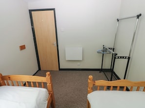 A room with two wooden beds, a door, a radiator, and a handrail. - Cabin No. 16 - Salt and Fern Cabins (Port Talbot)