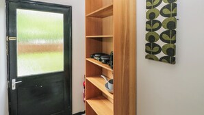 Una habitación con una puerta negra, un estante de madera y una pared con un diseño geométrico.