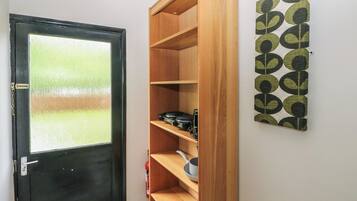 Una habitación con una puerta negra, un estante de madera y una pared con un diseño geométrico.
