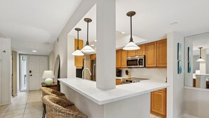 Una cocina moderna con una isla central, iluminación colgante y armarios de madera.