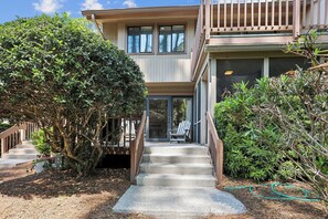 A two-story house with a covered porch, a staircase leading to the entrance, and a well-maintained garden.