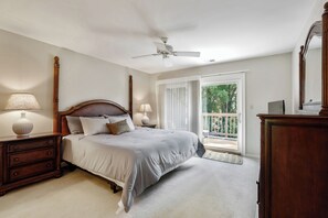 A bedroom with a bed, nightstands, a dresser, a ceiling fan, and a window with blinds.