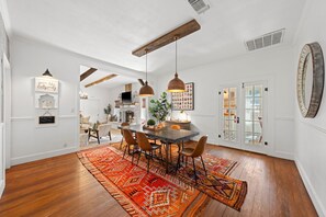 A dining area with a wooden table, chairs, and a patterned rug. - Poplar Place Main - Hot Tub & Fire Pit (Fredericksburg)
