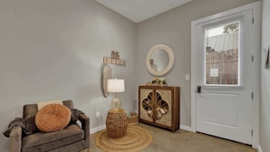 A living room with a sofa, a lamp, a cabinet, and a door with blinds. - Poplar Place 3 - Hot Tub & Close to Downtown (Fredericksburg)