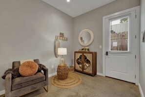 A living room with a sofa, a lamp, a cabinet, and a door with blinds. - Poplar Place 3 - Hot Tub & Close to Downtown (Fredericksburg)