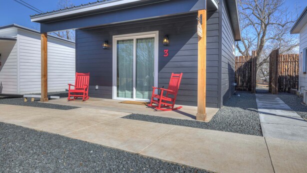 A house with a covered patio, two red chairs, and a sliding glass door. - Poplar Place 3 - Hot Tub & Close to Downtown (Fredericksburg)