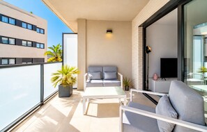 A balcony with a seating area, a TV, and potted plants. - Arenal Dream Glow Apartment Jávea (Javea / Xàbia)