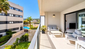 A balcony with a pool, white furniture, and a TV. - Arenal Dream Glow Apartment Jávea (Javea / Xàbia)