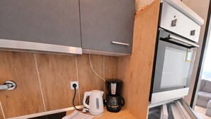 Eine moderne Küche mit Holzschränken, einer Kaffeemaschine und einem eingebauten Backofen.