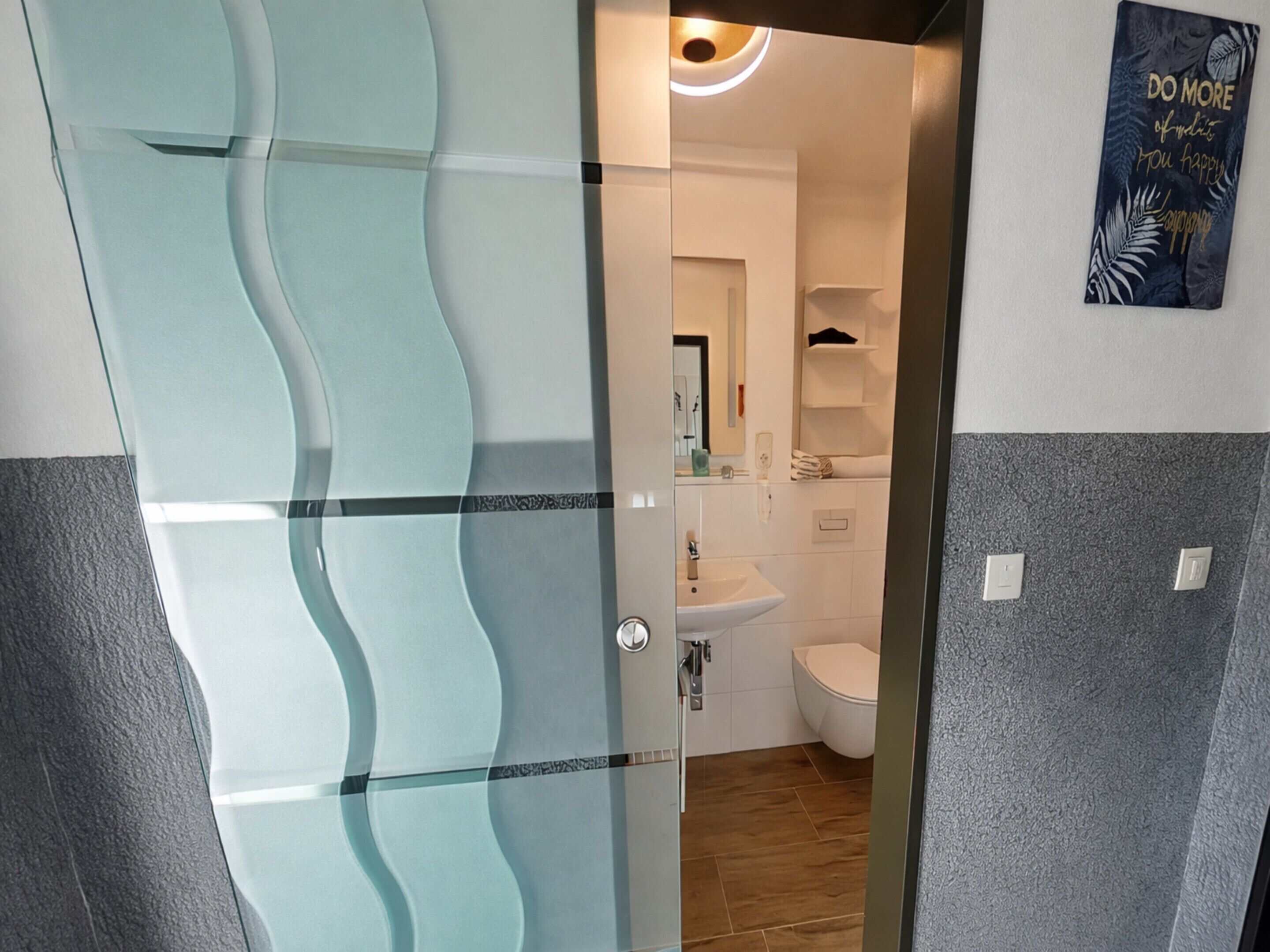 Ein modernes Badezimmer mit Glasdusche, Waschbecken und Toilette.