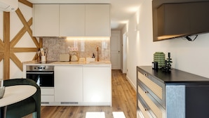 Une cuisine moderne avec des meubles blancs, un four encastré et un plan de travail sur lequel se trouve un grille-pain.