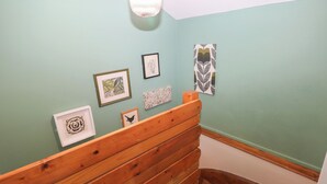 Un pasillo con un banco de madera, pared de color verde claro y varias obras de arte enmarcadas.