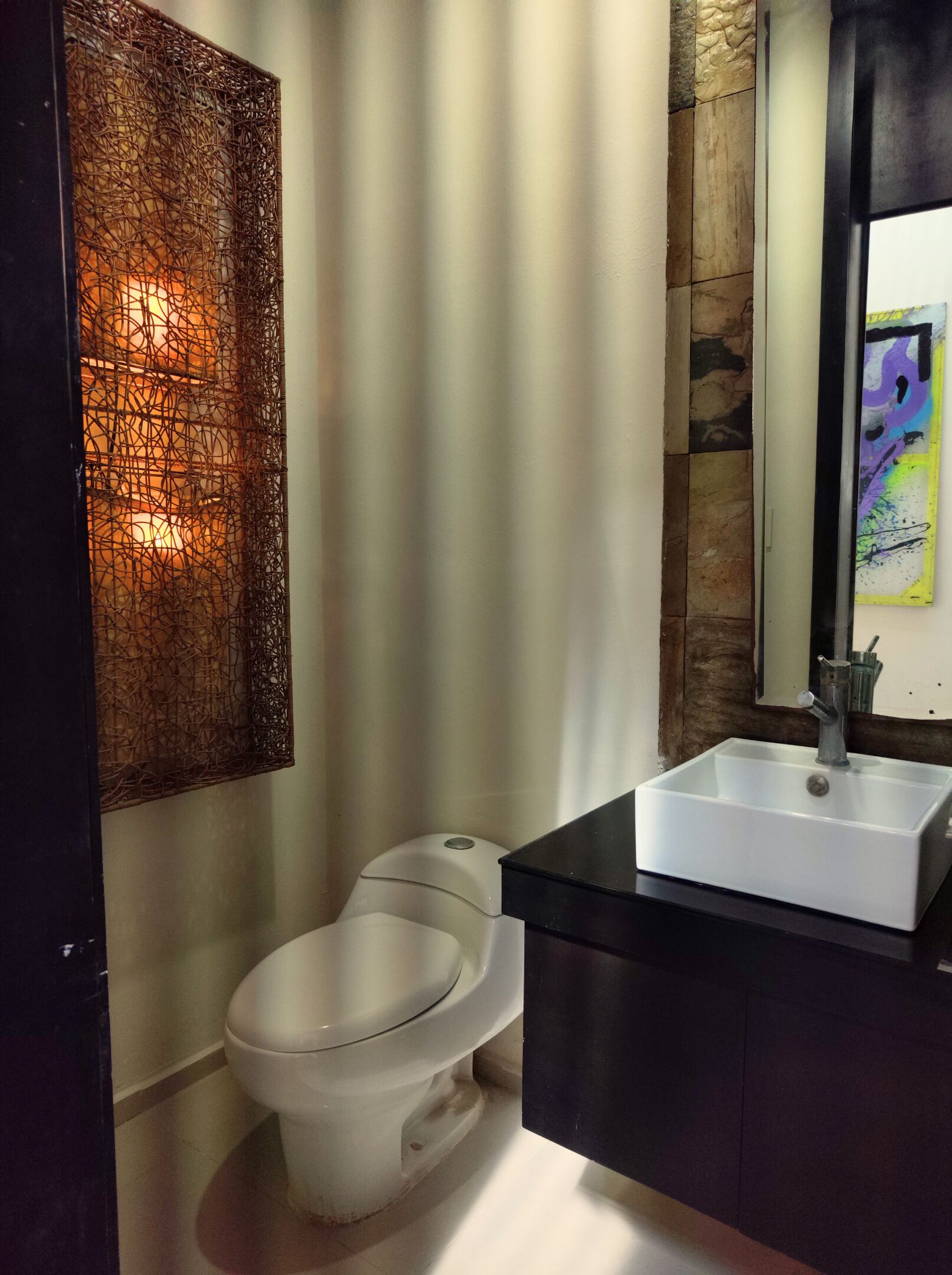 A modern bathroom with a toilet, a white sink, and a decorative wall panel.